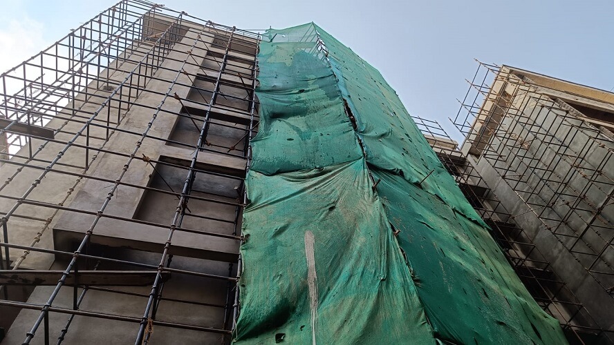 Green screen cover over the scaffolding is used to paint the exterior.