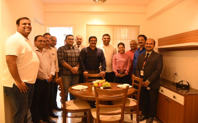 A group photo of the team was taken in a living room with dim lights as the background.